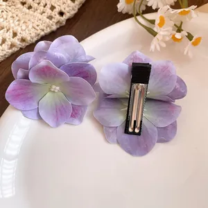Dettaglio macro di fermagli per capelli a fiore in tessuto viola con petali e becco d'anatra