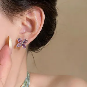 Close-up detail of elegant purple zircon flower stud earrings worn on the earlobe