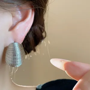 Detail view of textured silver oval stud earrings showing the horizontal line pattern