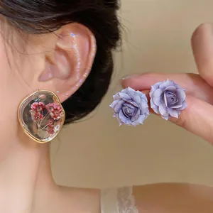 Dettaglio degli orecchini a lobo rosa viola e resina trasparente con fiori secchi