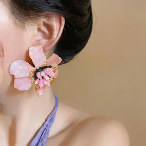 Close-up of pink enamel flower earrings with silver needles and intricate center detail