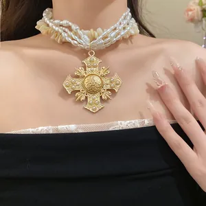 Close-up of multi-layer pearl and shell necklace with ornate golden cross pendant