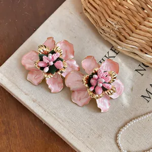 Close-up detail of pink enamel flower earrings with intricate gold-toned metal accents.