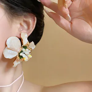 Detailed view of heavy workmanship flower stud earrings with pearlescent petals on ear