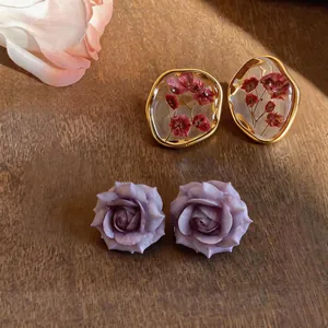 Dettaglio macro squisito di orecchini floreali fatti a mano con resina e petali di rosa.