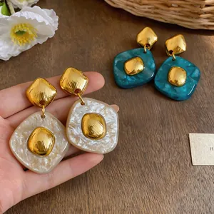 Close-up view of resin diamond-shaped earrings with marble texture in cream and teal