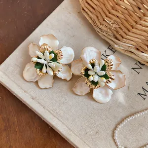 Detailed macro shot of exquisite cream and gold flower earrings with glossy oil finish