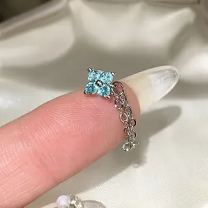 Close-up view of elegant zircon flower stud earrings with a delicate hanging silver chain
