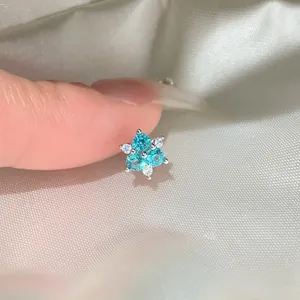 Close-up of zircon flower stud earring with turquoise and clear stones on satin.