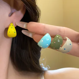 Close-up of colorful polka dot C-shaped earrings featuring a glossy drip oil finish design