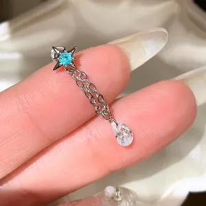 Close-up of a silver star stud earring with blue gem and zircon teardrop dangle