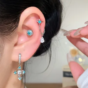 Detailed macro view of silver-toned cross and star earrings featuring vibrant blue zircon stones