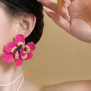 Close-up view of a vibrant pink flower earring with gold edges on an Asian model's ear.