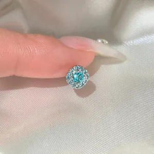 Close-up macro detail of a square silver stud earring featuring a sparkling turquoise zircon