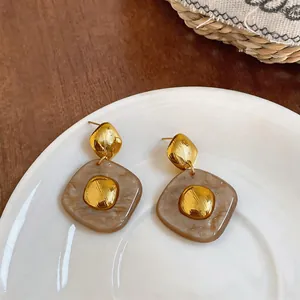 Detailed shot of marbled brown resin square earrings with gold metallic accents