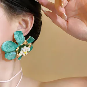 Close-up detail of a large teal flower earring with an intricate white floral center piece