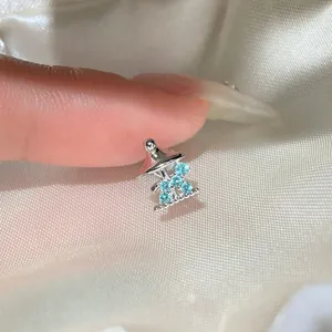 Macro detail of a silver stud earring with light blue zircons on textured silk background.