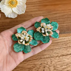 Close-up detail showing green enamel flower earrings with elegant gold accents