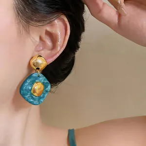 Close-up of vintage resin rhombus drop earrings with golden textured metal accents