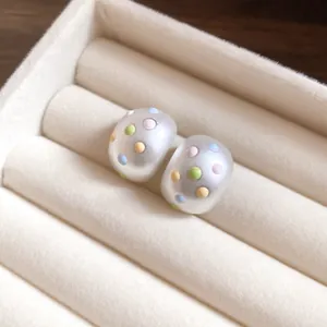 Eleganti orecchini a perno ovali opachi con pois colorati in un portagioie in velluto