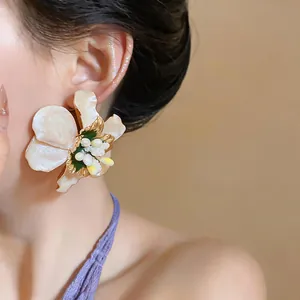 Detailed close-up view of an elegant cream floral drop earring worn by a female model