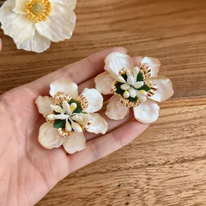 Macro view of exquisite drip oil flower earrings with golden textured details.
