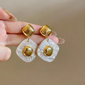 Detailed shot of gold and white marble textured resin rhombus drop earrings