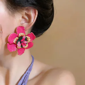 Close-up detail of vibrant pink enamel flower stud earring worn by model for elegant style