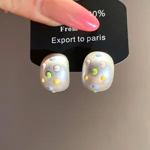 Primo piano di orecchini ovali opachi con pois in smalto colorato e ago in argento