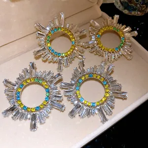 Gros plan de quatre boucles d'oreilles soleil avec des strass colorés et des cristaux.