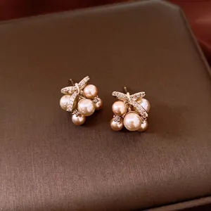 Elegant cluster pearl stud earrings with zircon accents on a textured jewelry box background