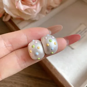Dettaglio degli orecchini a perno ovali opachi con pois in smalto colorato e perno