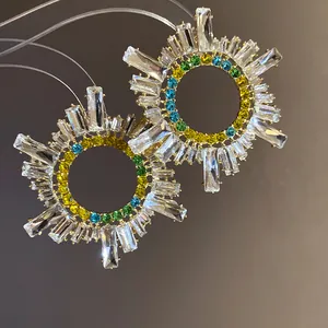 Vue détaillée des boucles d'oreilles circulaires avec cristaux clairs et colorés.