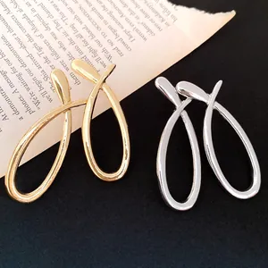 Detailed view of polished cross-over hollow stud earrings in gold and silver finish