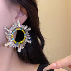 Vue détaillée de boucles d'oreilles soleil rayonnantes avec strass multicolores