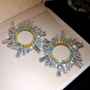 Vue détaillée de boucles d'oreilles soleil avec cristaux colorés et pierres baguette.