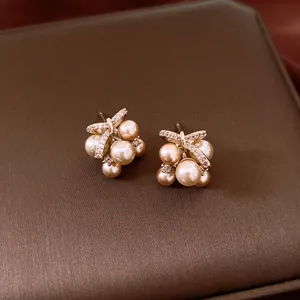 Macro shot of elegant champagne pearl stud earrings with zircon butterfly bow detail