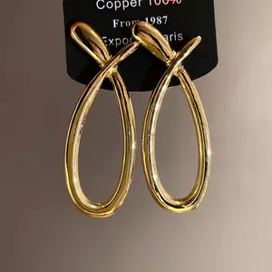 Detailed view of premium gold-tone cross-over hollow drop earrings with smooth finish