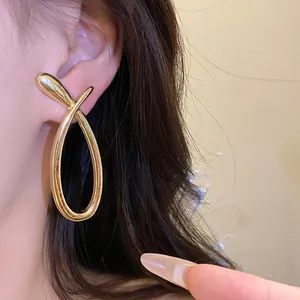 Detailed close-up showing the elegant gold cross hollow earring design worn on ear
