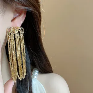 Detailed macro shot of elegant gold firework tassel statement earrings worn by a model