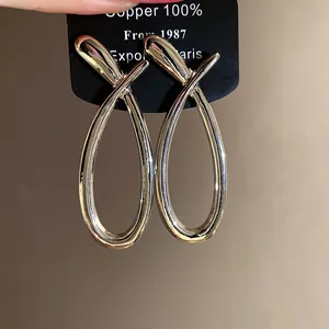 Close-up of minimalist polished crossed hollow loop earrings on black display card