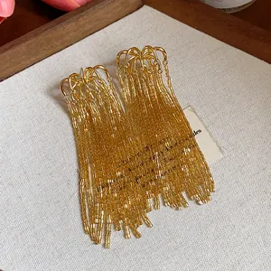Detailed macro view of golden glass bead firework tassel earrings with silver needles.