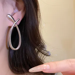 Close-up detail showing the wearing effect of minimalist silver hollow cross earrings.