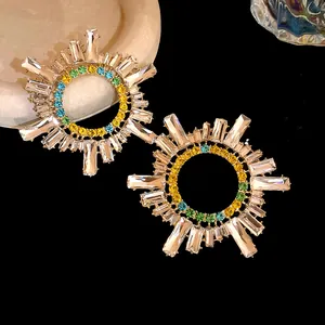 Gros plan sur des boucles d'oreilles soleil avec des strass colorés sur fond noir