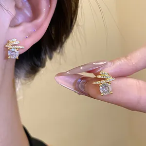 Detailed close-up of gold spiral earrings with large round cubic zirconia stones