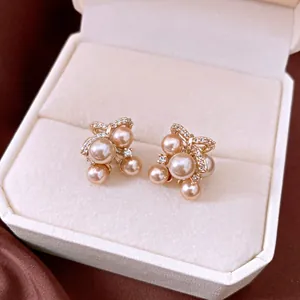 Close-up of elegant champagne pearl stud earrings with zircons in a white velvet box
