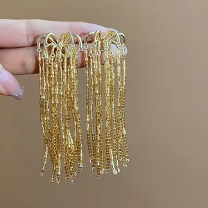 Detailed view of gold-tone tassel earrings featuring fireworks style glass beads