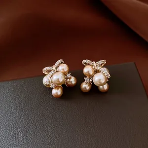 Close-up of elegant champagne pearl cluster stud earrings with zircon bow detailing