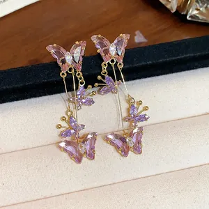 Gros plan d'élégantes boucles d'oreilles papillon en zircone violette sur un écrin