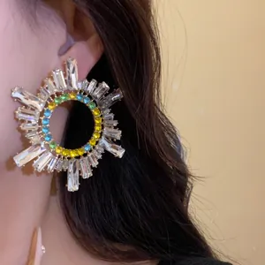 Gros plan d'un mannequin portant des boucles d'oreilles colorées en strass et argent